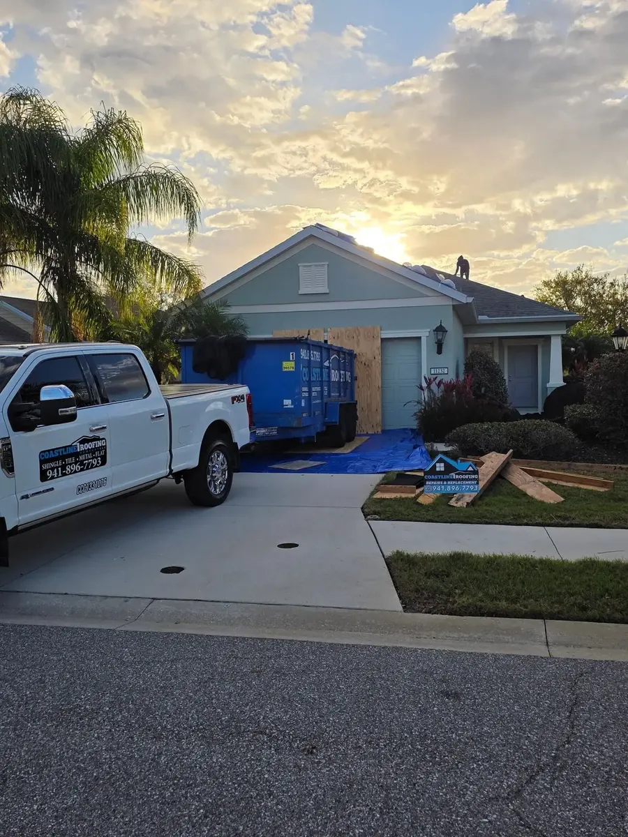 Coastline Roofing truck and dumpster on a job site at sunset